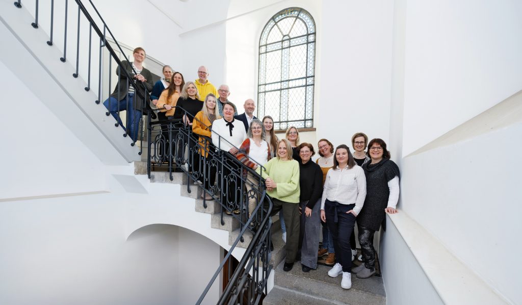 Foto Gesamtteam der Ökumenischen Hospizinitiative im Landkreis Ludwigsburg im Turm auf der Treppe der Stadtkirche